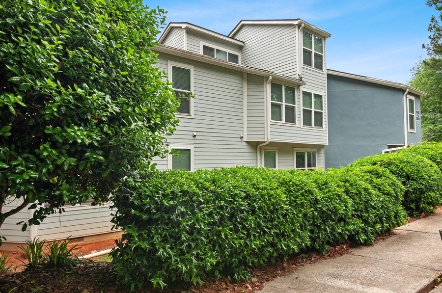 Apartment building exterior showcasing well kept landscape and shrubbery.