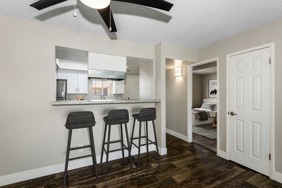 a kitchen with a breakfast bar and three stools in front of it at Villages at Metro Center, Phoenix, AZ