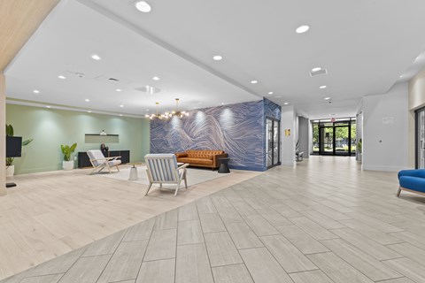 A spacious lobby with a blue and white abstract wall art, a wooden bench, and a blue sofa.