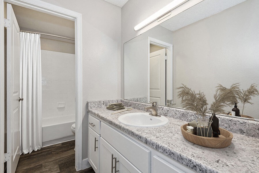 Model Bathroom with White Cabinets, Wood-Style Flooring and Shower/Tub at Peaks on 4th Apartments in Avondale, AZ.