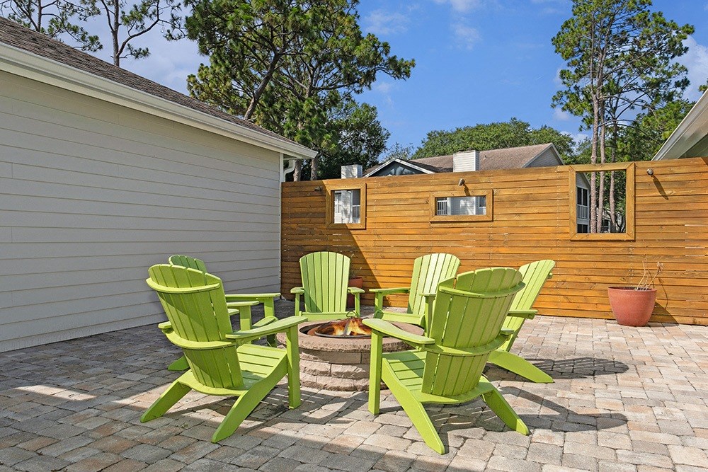 Fire pit with 4 green adirondack chairs on a brick patio at Retreat at Crosstown Apartments