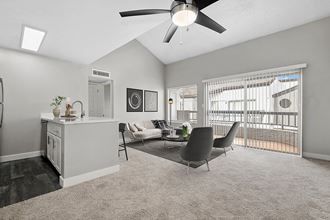 Model Living Room with Carpet and View of Kitchen with Wood-Style Flooring at Crystal Creek Apartments in Phoenix, AZ.