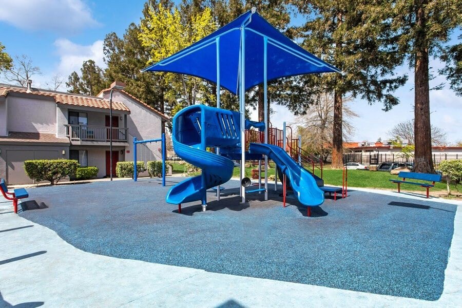 Community Playground with a Slide, Swing Set and Blue Canopy at Creek 2645 Apartments in Sacramento, CA.