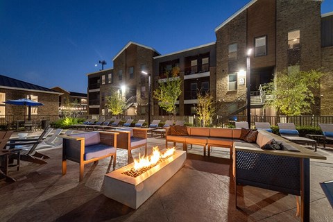 Outdoor Fire Pit Area with Lounge Furniture and View of Pool at Alta 3Eighty Apartments located in Aubrey, TX.