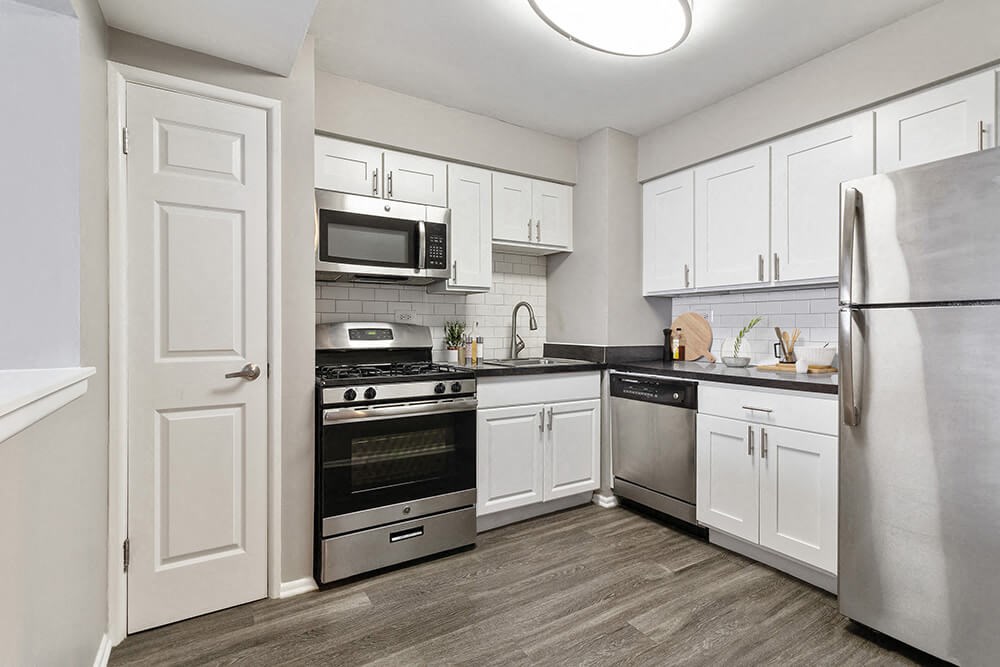Model Kitchen with White Cabinets and Wood-Style Flooring at Midpointe Apartments in Chicago, IL.