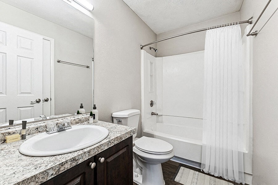 Model Bathroom with Dark Cabinets, Wood-Style Flooring and Shower/Tub at Paramont Apartments in Duluth, GA.