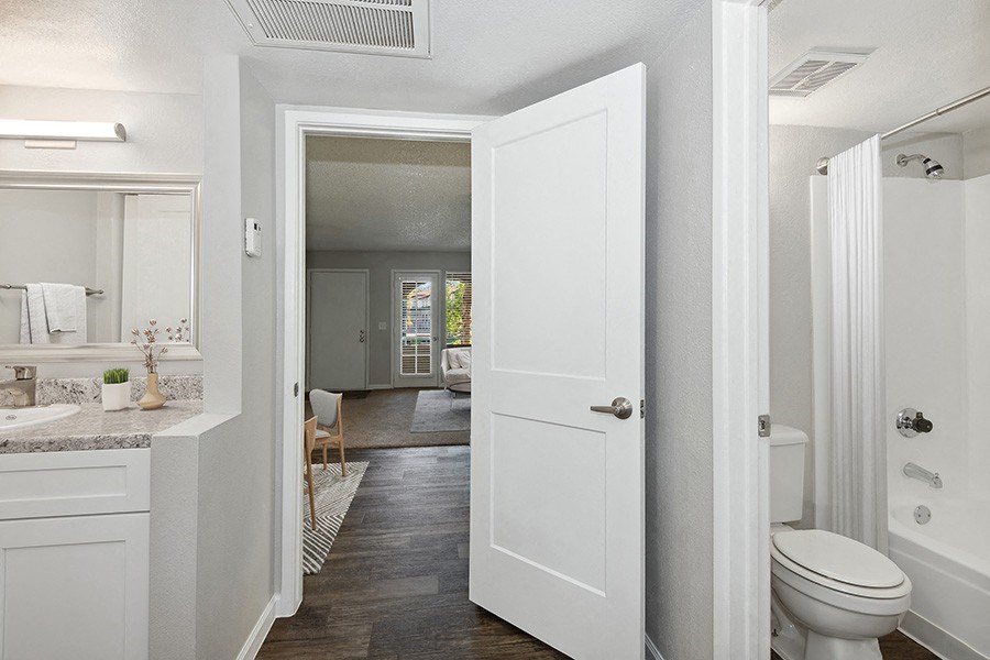 Model Master Bathroom with White Cabinets and Wood-Style Flooring at Stillwater Apartments in Glendale, AZ.