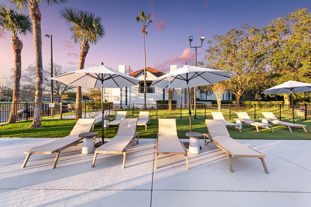 a group of lounge chairs with umbrellas in a park