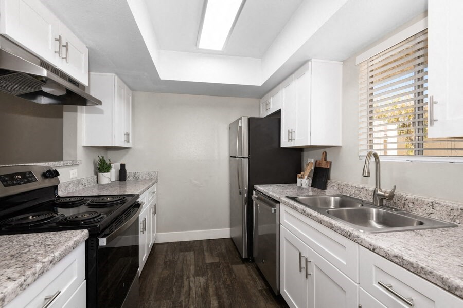 a kitchen with white cabinets and black appliances at Villages at Metro Center, Phoenix, Arizona