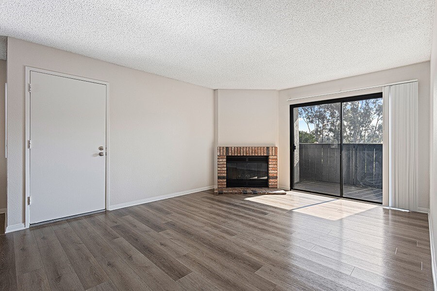 Model Living Room with Wood-Style Flooring, Fireplace and Patio Accessibility at Santa Fe Ranch Apartments located in Carlsbad, CA.