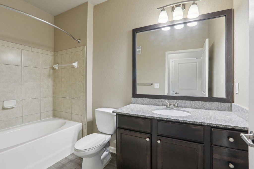 Model bathroom with a white toilet, sink, and bathtub.