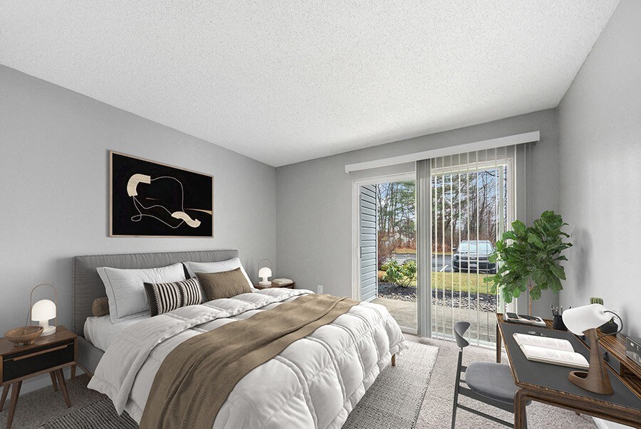 Model Bedroom with Carpet and Patio Accessibility at Commons at Haynes Farm Apartments in Shrewsbury, MA.