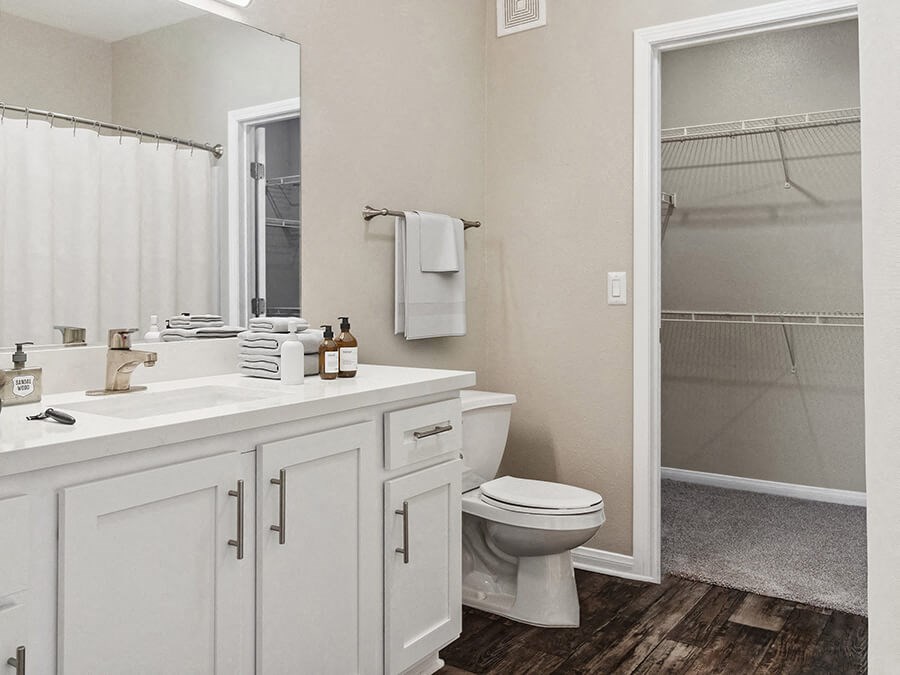 Model Bathroom with White Cabinets, Wood-Style Flooring & Walk In Closet at Reserve at Rancho Apartments located in Moreno Valley, CA.