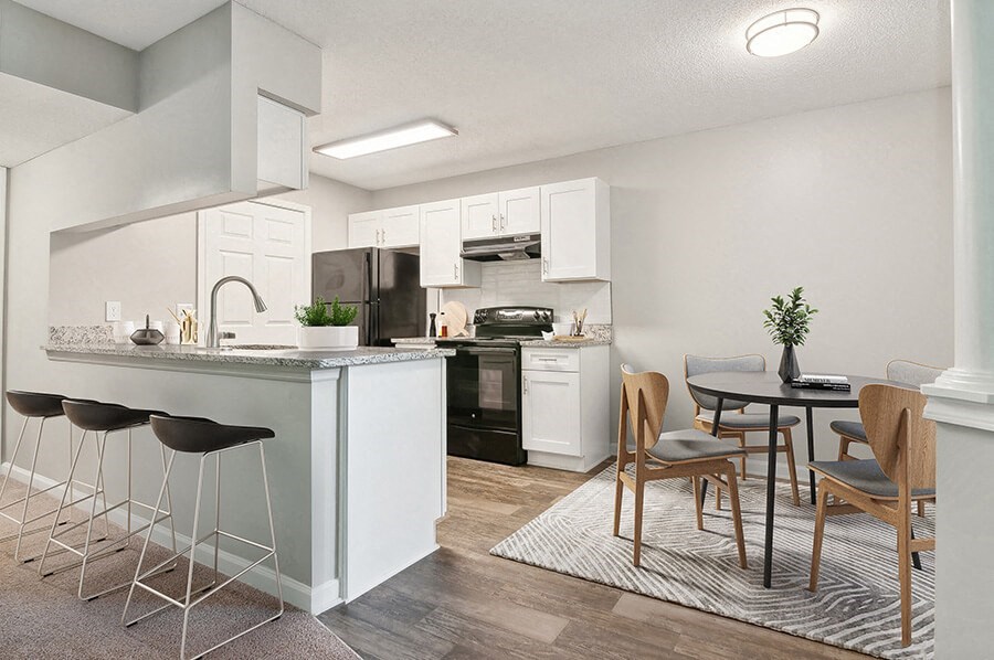 Model Dining Room and Kitchen with Wood-Style Flooring and White Cabinets at Park 2300 Apartments in Charlotte, NC.