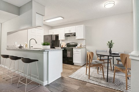 Model Dining Room and Kitchen with Wood-Style Flooring and White Cabinets at Park 2300 Apartments in Charlotte, NC.