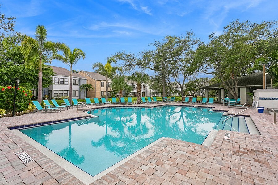 Community Swimming Pool with Pool Furniture at Huntington Place Apartments located in Sarasota, FL.