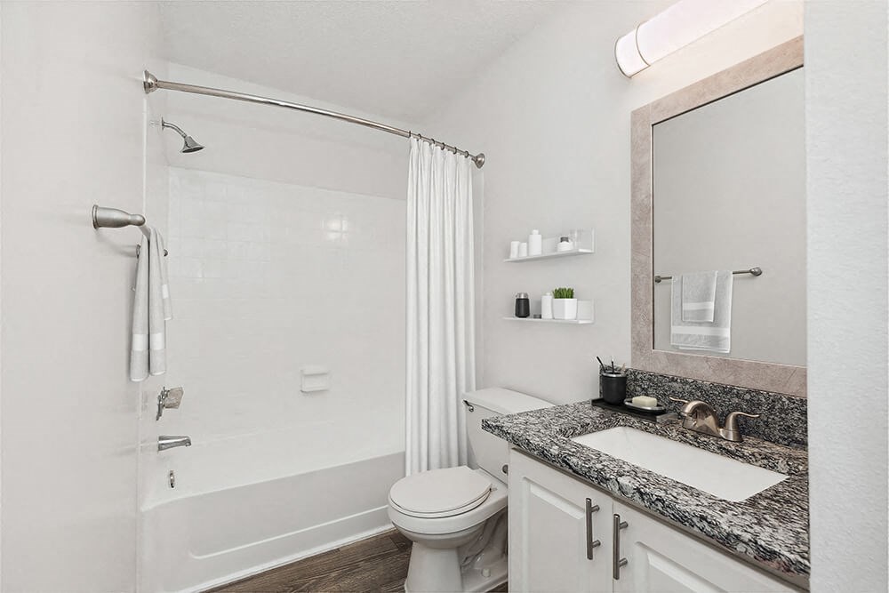 Model Bathroom with White Cabinets and Wood-Style Flooring at Seven Lakes at Carrollwood Apartments in Tampa, FL.