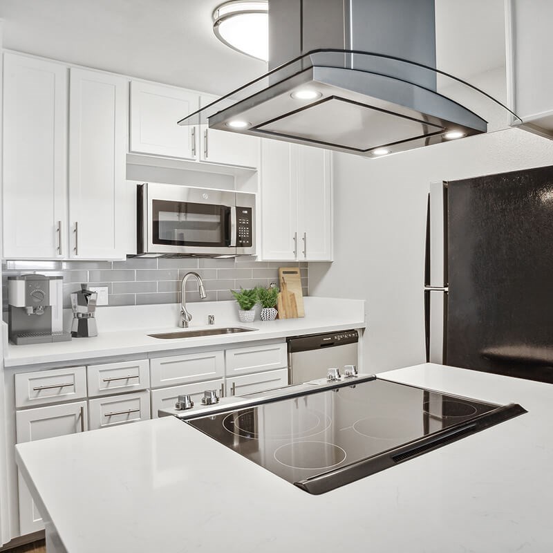 Model Kitchen with White Cabinets and Wood-Style Flooring at Cove La Mesa Apartments located in La Mesa, CA.