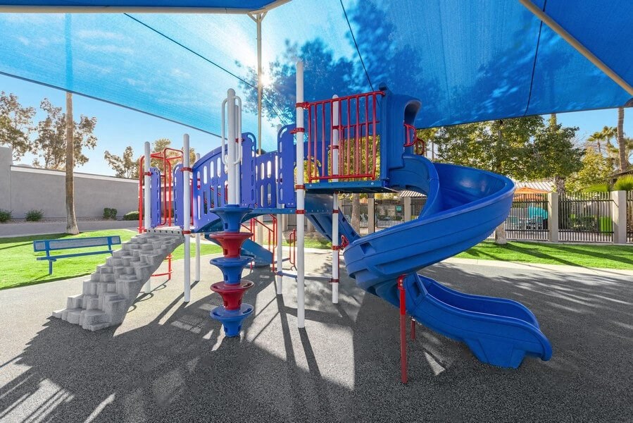 Community Playground with slide, rock wall climb, and blue canopy at Lakeside Casitas in Tucson, AZ.