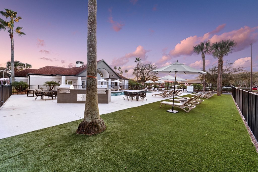 a resort style pool with lounge chairs and umbrellas