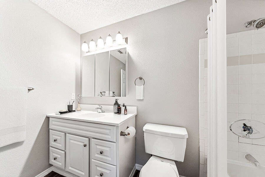 Model Bathroom with White Cabinets, Wood-Style Flooring and Shower/Tub at Commons at Haynes Farm Apartments in Shrewsbury, MA.