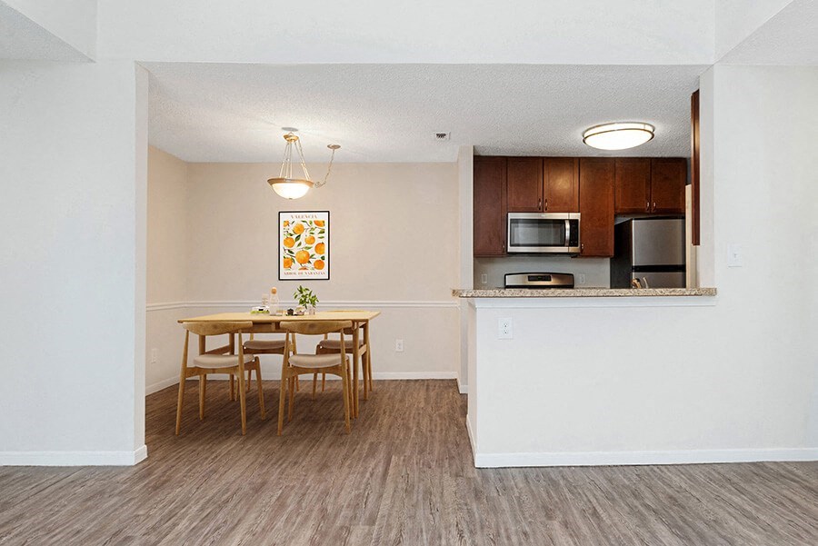 Model Dining Room and Kitchen Area with Wood-Style Flooring at The Commons at Haynes Farm Apartments in Boston, MA.