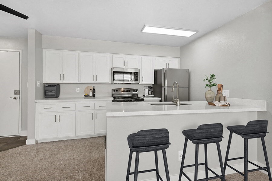 Model Kitchen with White Cabinets and Wood-Style Flooring at Crystal Creek Apartments in Phoenix, AZ.