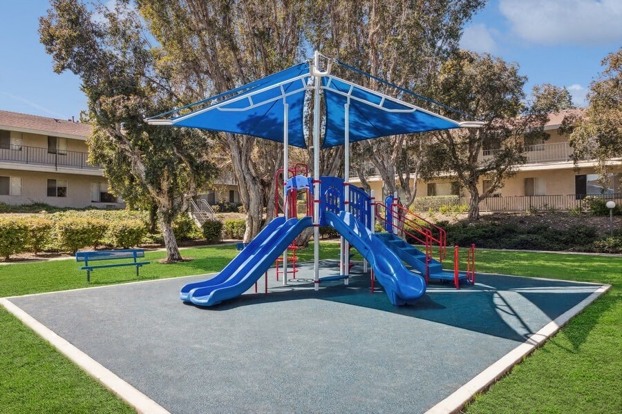 Community Playground with Two Slides and a Blue Canopy at Forest Park Apartments in El Cajon, CA.