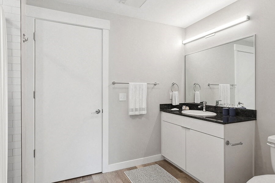 Model Bathroom with Wood-Style Flooring, White Cabinets & Shower/Tub at Seven Skies Apartments located in Sandy, UT.