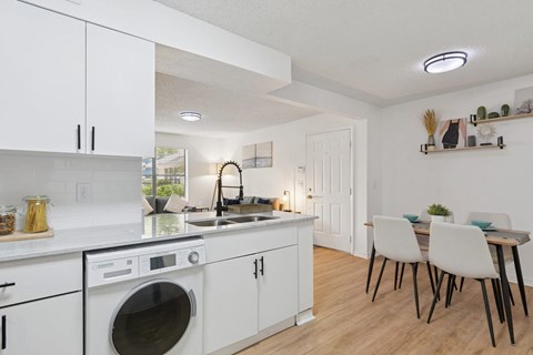 A modern kitchen with white cabinets and a wooden floor.