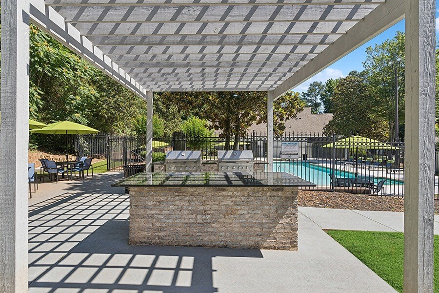Outdoor BBQ Area with Canopy and View of Swimming Pool at Retreat at Stonecrest Apartments located in Lithonia, GA.