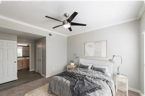 North Dallas, TX Apartments Near Arbor Hills Nature Preserve - Essence North Dallas - Bright Bedroom With Plush Carpet, Nightstands With Lamps, Ceiling Fan, And Private Bath Entry.