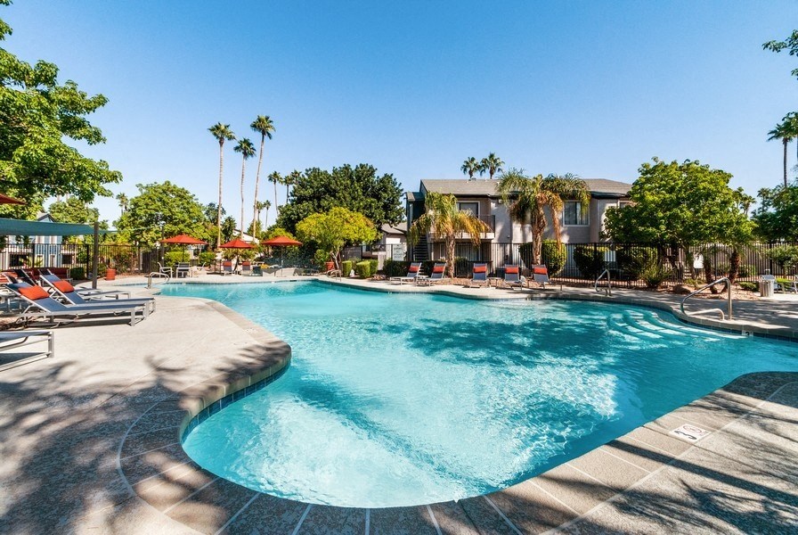 Pool with apartment building and tree in background