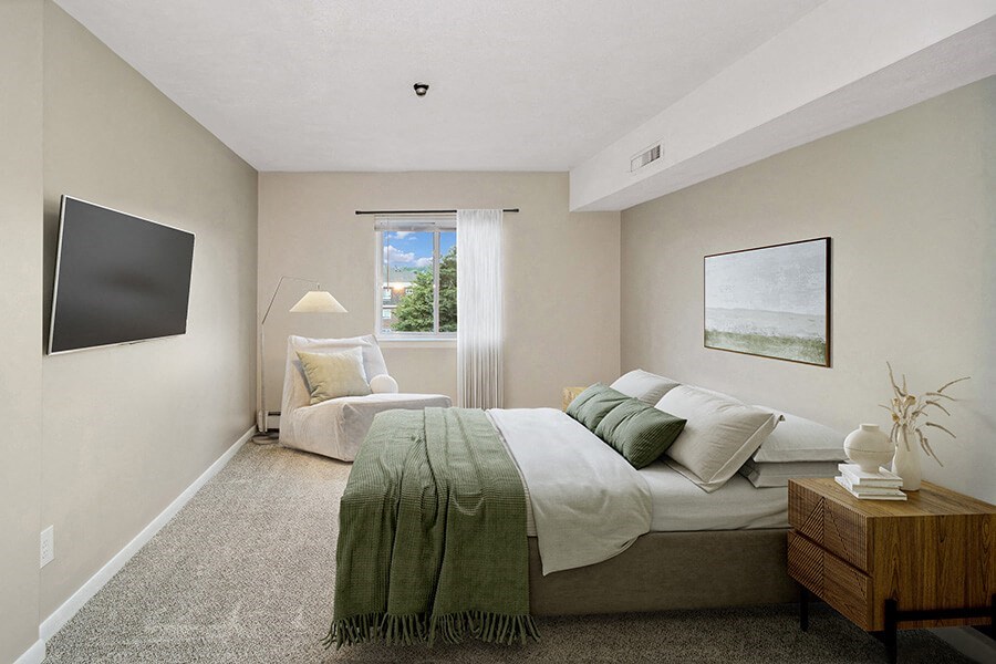 Model bedroom with a bed and a window at Stone Ends apartments in Stoughton, MA