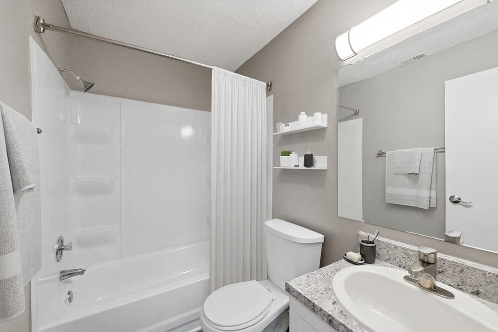 Model Bathroom with White Cabinets, Wood-Style Flooring and Shower/Tub at Spring Forest Apartments in Raleigh, NC.