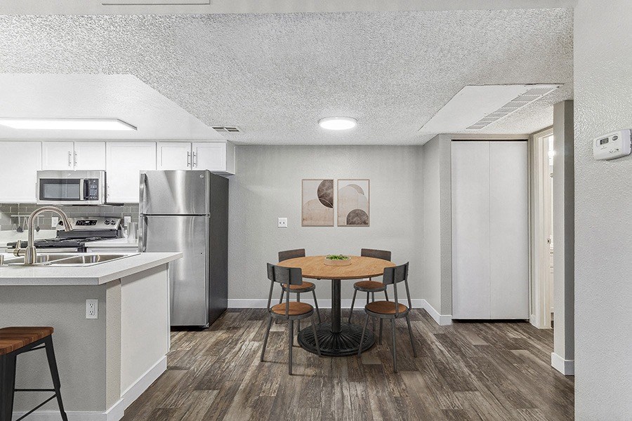 Model Dining Room and Kitchen Area with Wood-Style Flooring at Meadow Ridge Apartments in Las Vegas, NV.