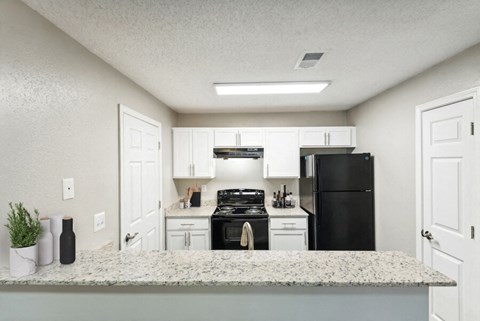 a kitchen with white cabinets and a black refrigerator
