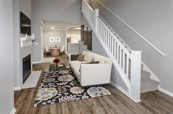 Model Living Room Staircase Model Living room with kitchen/dining in background and stairs going up. - Photo Gallery 3