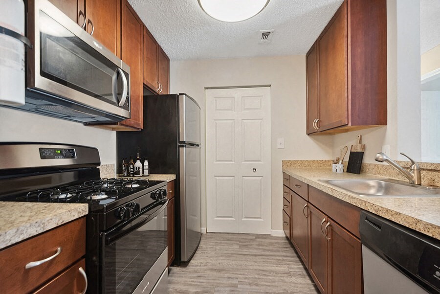 Model Kitchen with Brown Cabinets and Wood-Style Flooring at The Commons at Haynes Farm Apartments in Boston, MA.