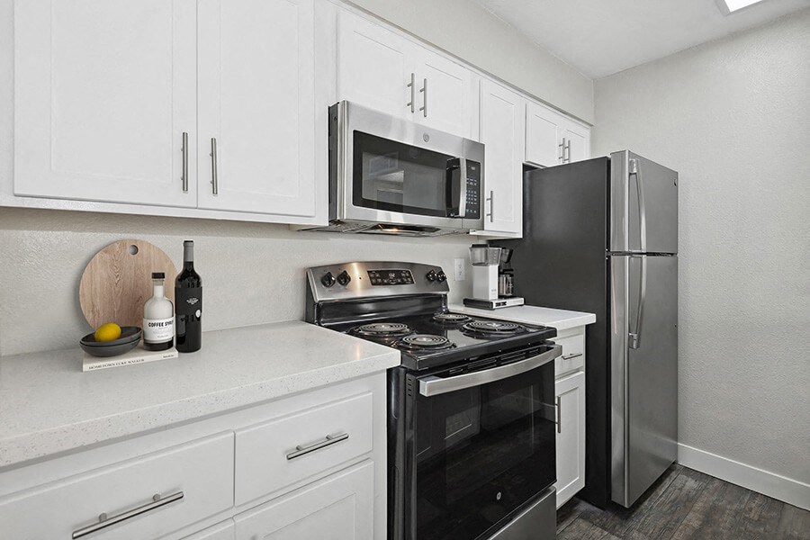 Model Kitchen with White Cabinets and Wood-Style Flooring at Crystal Creek Apartments in Phoenix, AZ.