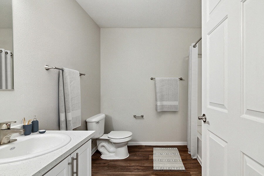 Model Bathroom with Bathtub/Shower, Wood-Style Flooring & White Cabinets at Loma Vista Apartments in Las Vegas, NV.