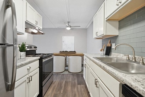 Model Kitchen with White Cabinets and Wood-Style Flooring at Parkvue Flats Apartments in Burnsville, MN.
