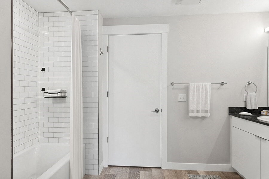 Model Bathroom with Wood-Style Flooring, White Cabinets & Shower/Tub at Seven Skies Apartments located in Sandy, UT.