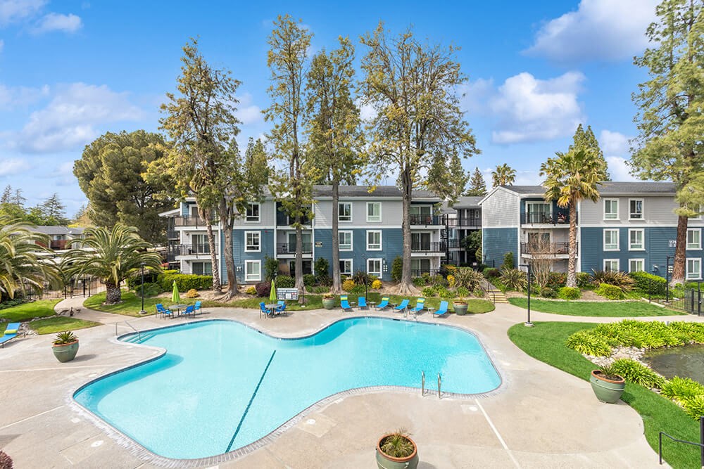 Community Swimming Pool with Pool Furniture at Fountains at Point West Apartments in Sacramento, CA.