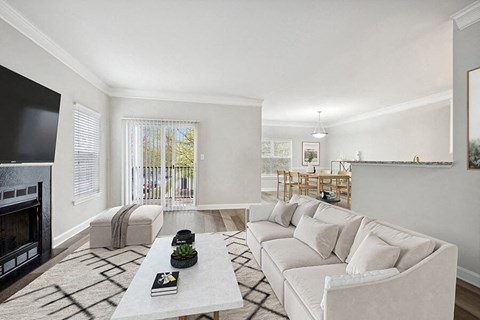 Model Living Room with Wood-Style Flooring, Fireplace and Patio Accessibility at Dulles Green Apartments located in Herndon, VA.