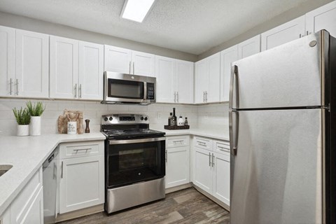a white kitchen with stainless steel appliances and white cabinets