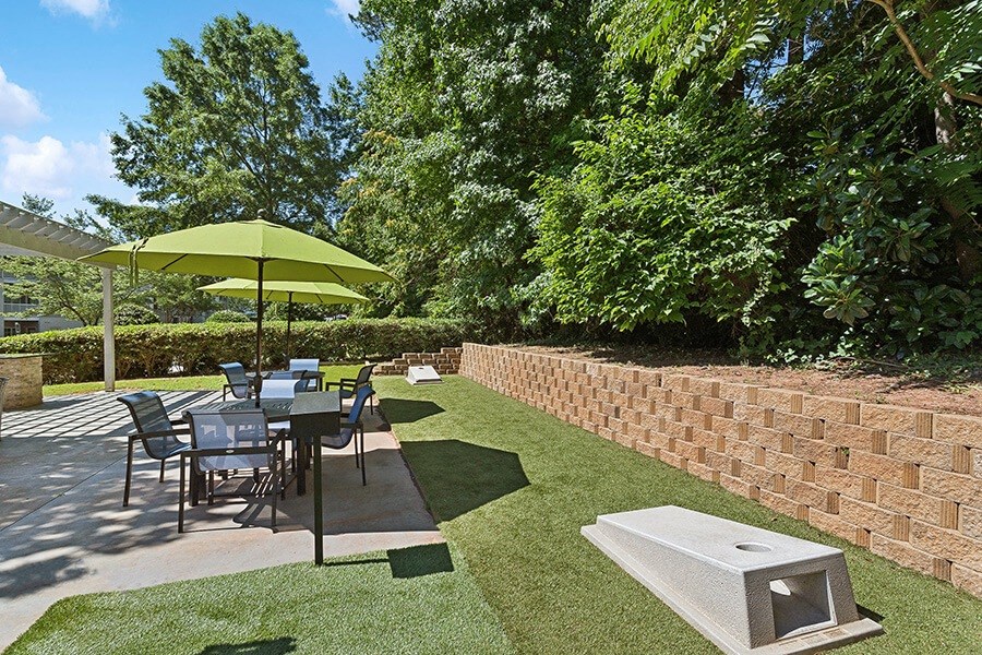 Outdoor Picnic Area with Lounge Furniture and Corn Hole Sets at Retreat at Stonecrest Apartments located in Lithonia, GA.