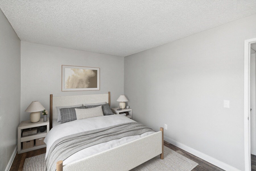 a bedroom with white walls and a bed with a gray blanket