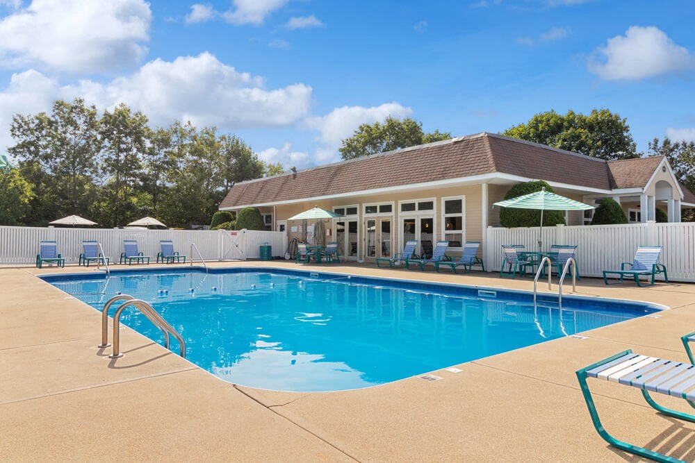 Swimming pool with lounge chairs and umbrellas near clubhouse