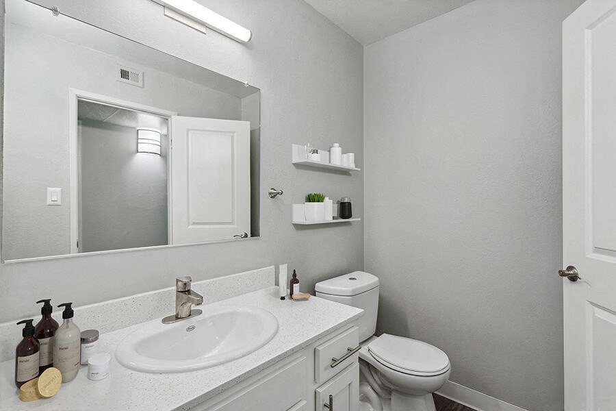 Model Bathroom with White Cabinets and Wood-Style Flooring at The Archer Apartments in Sacramento, CA.